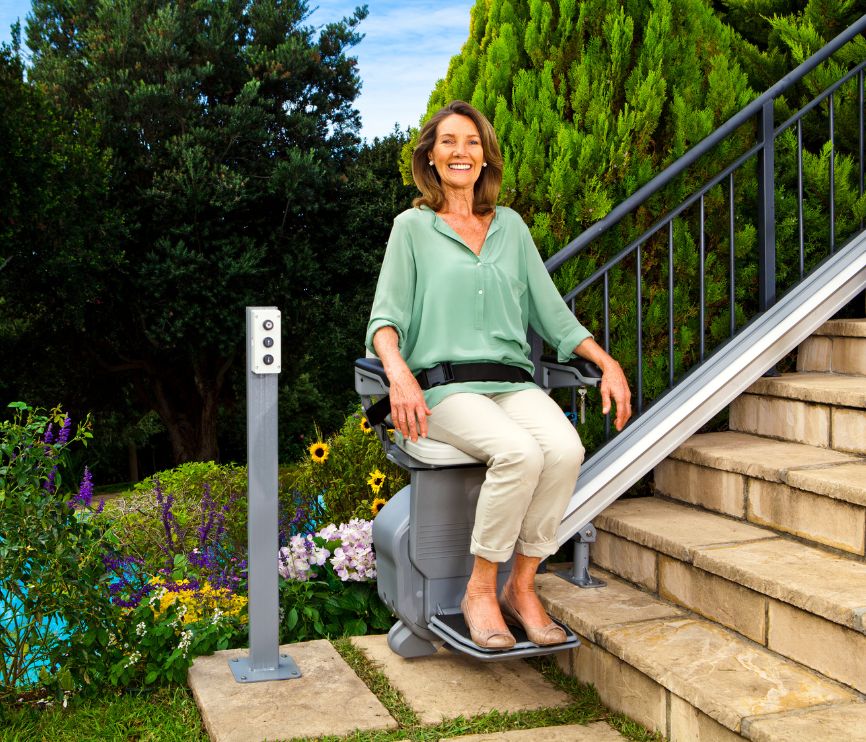 Happy woman sat on an outdoor stairlift for straight stairs.