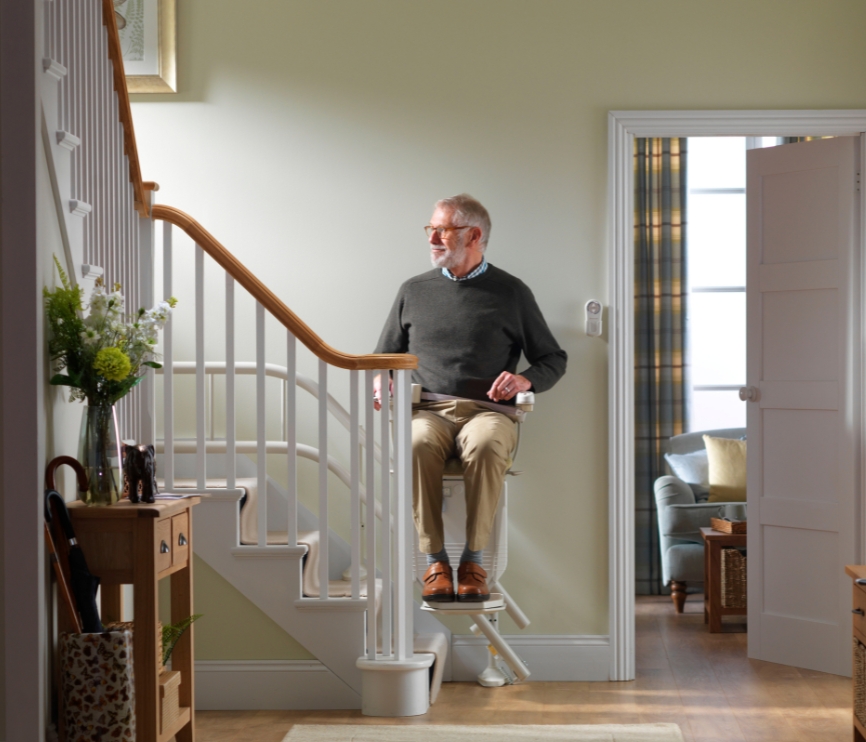 A man is going up the stairs with a Stannah stairlift for curved stairs