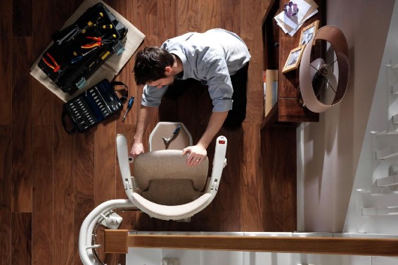Stannah technician performing maintenance on a Stannah stairlift.